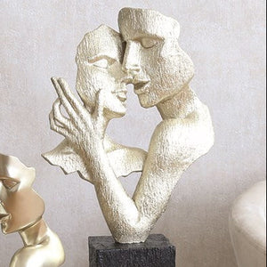 Two abstract sculptures of people on a table against a neutral background