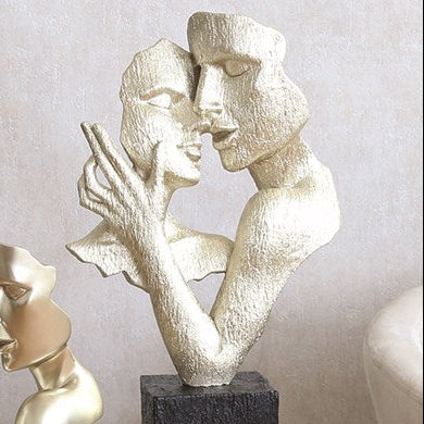 Two abstract sculptures of people on a table against a neutral background